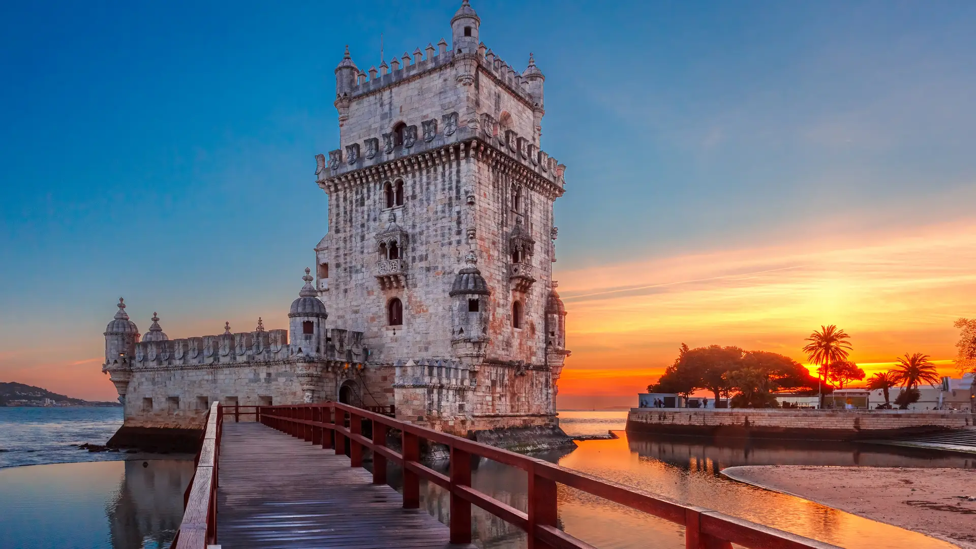Portugal Golden Visa 2026 1 Belém Tower in Lisbon illuminated at sunset with a wooden bridge in the foreground, highlighting historic destinations accessible via Portugal Golden Visa 2026.